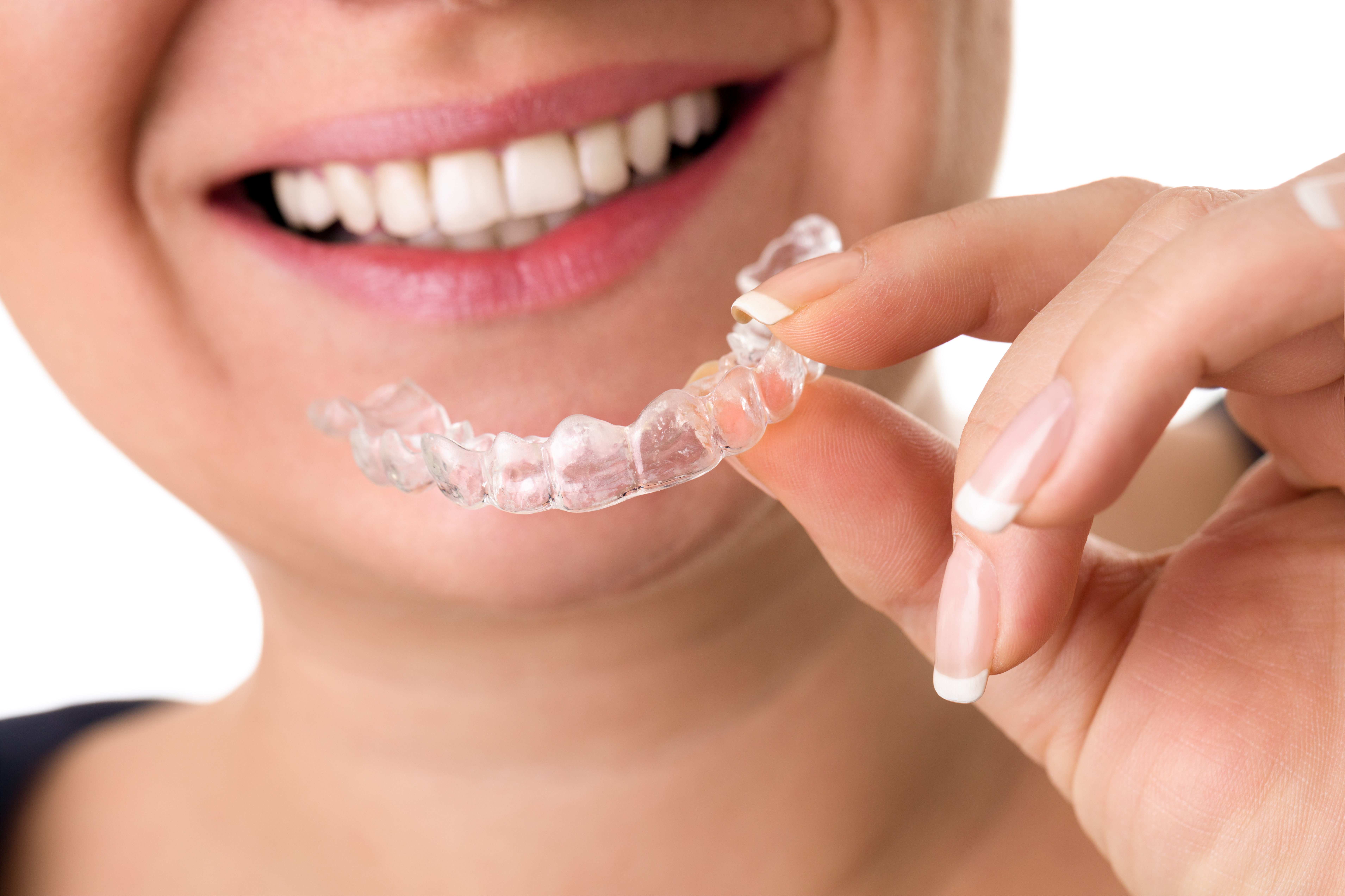 smiling female holding invisible teeth braces